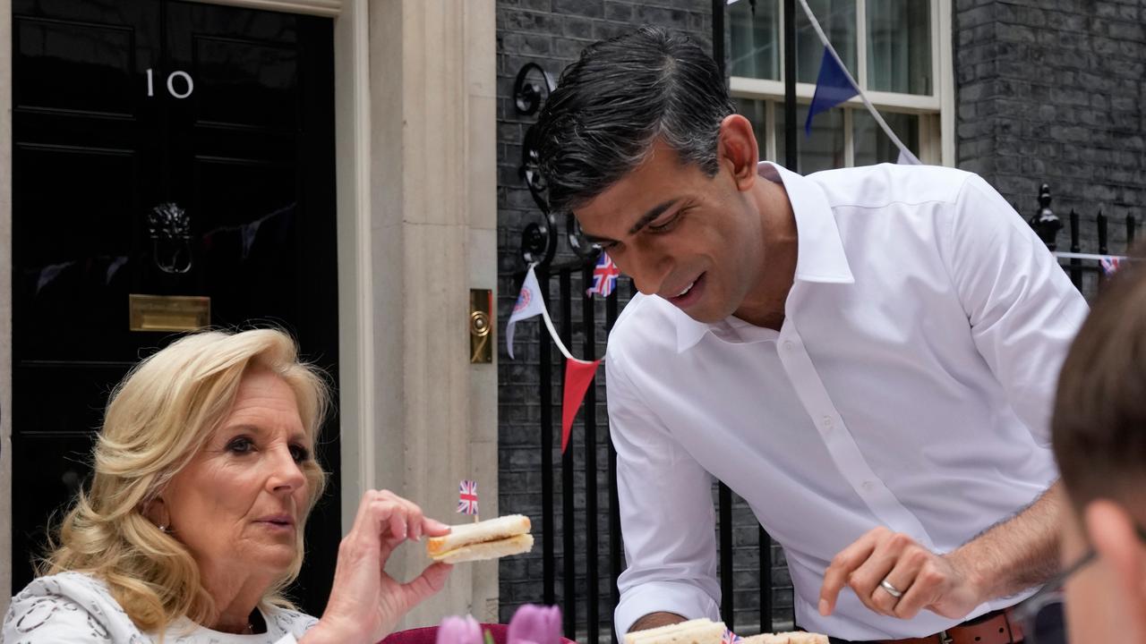 Britain's Prime Minister Rishi Sunak holds a plate of sandwiches as US First Lady Jill Biden takes one with a British flag. Picture: Getty Images