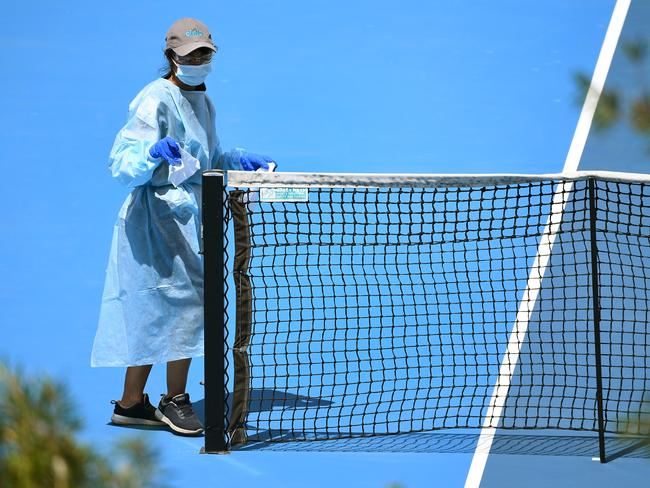 A cleaner wipes down the net after a player's practice session in Melbourne. Picture: William West/AFP