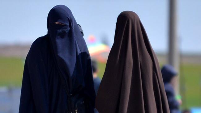 Unidentified women, reportedly wives of a suspected Islamic State fighters, walk at a refugee camp in Syria. Four former brides have been repatriated to Australia, where they are under police surveillance. Picture: EPA/Murtaja Lateef