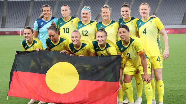 The Australian team poses with the Aboriginal flag before their match against New Zealand. Picture: AFP