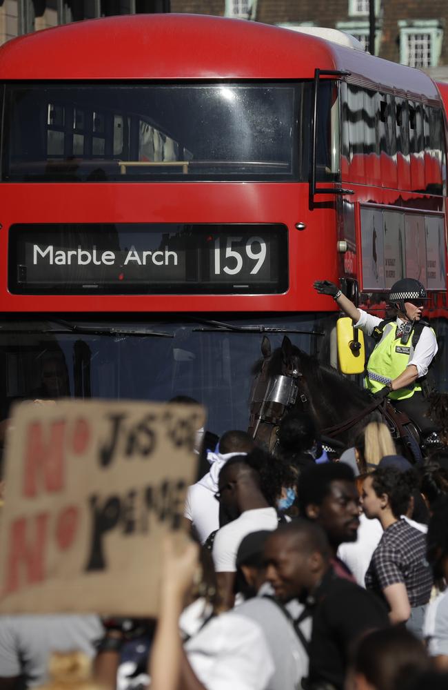 Police officers on horseback stand next to demonstrators blocking the road outside the Houses of Parliament in central London.