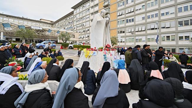 Nuns and priests pray at the statue of John Paul II outside the Gemelli University Hospital where Pope Francis is being treated. Picture: AFP