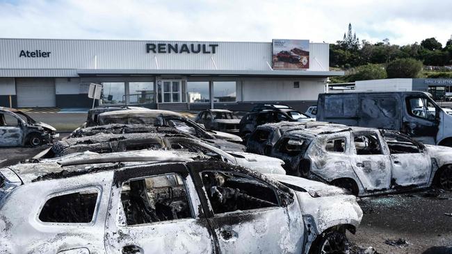 Burnt cars are pictured at a car dealer store in the Magenta district in Noumea.