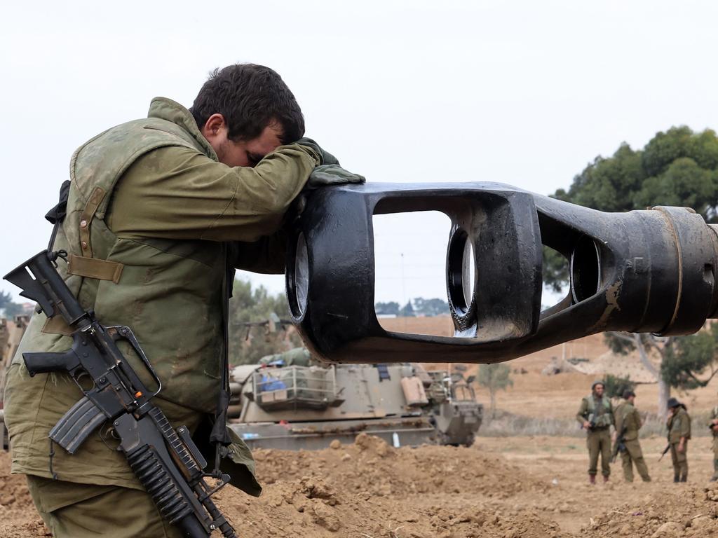 An Israeli soldier rests his head on an artillery gun barrel of an armoured vehicle as Israeli soldiers take positions near the border with Gaza in southern Israel. Picture: AFP