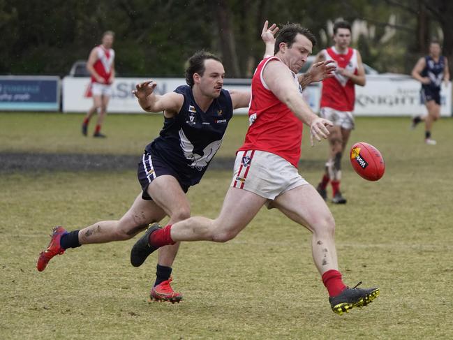 Red Hill’s Harry Larwill takes a kick as Edi-Asp’s Troy Brimble tackles. Picture: Valeriu Campan