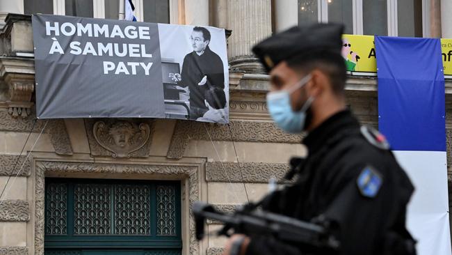 A French police officer stands next to a portrait of French teacher Samuel Paty on display on the facade of the Opera Comedie in Montpellier. Picture: AFP