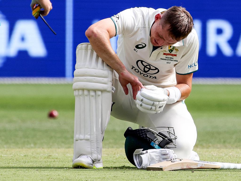 Australia's Marnus Labuschagne (C) inspects his injured finger.