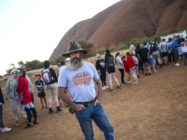 A man wearing a t-shirt saying 'I chose not to climb' stands next to tourists lining up to climb Uluru, also known as Ayers Rock at Uluru-Kata Tjuta National Park in the Northern Territory, Friday. Picture: AAP