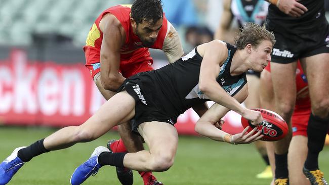 Port Adelaide’s Xavier Duursma tries to fire out the handball despite the pressure from Lions Jack Martin. Picture Sarah Reed