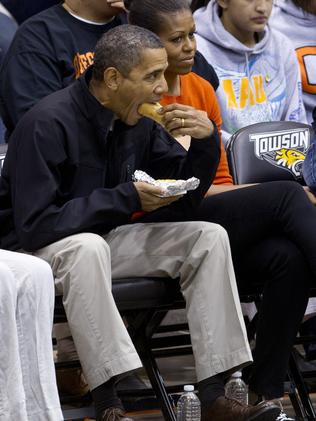 Former US President Barack Obama eating a hot dog at a basketball game. Picture: AP/Carolyn Kaster