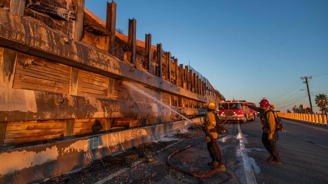 Firefighters spray water and soap to eliminate hotspots in a wooden wall next to the Getty Village Museum on January 12 in the Pacific Palisades neighbourhood of Los Angeles. Picture: Getty Images via AFP