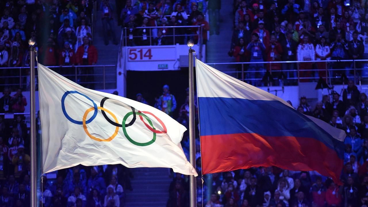 The Olympic flag (L) and the Russian flag flutter. Photo by Damien MEYER / AFP.