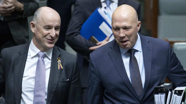 Government ministers Stuart Robert and Peter Dutton share a joke during a rain-affected question time on Monday. Picture: Gary Ramage