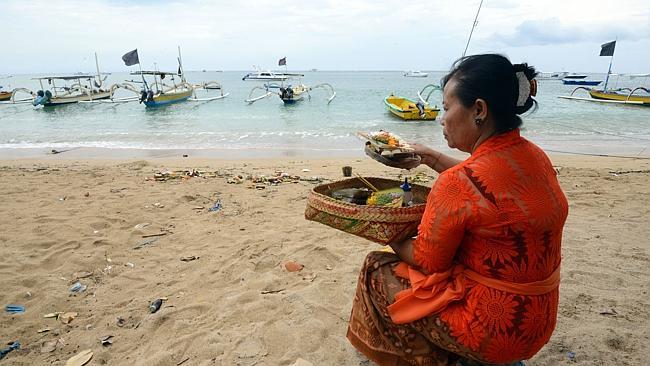 Horrific ordeal...A Balinese woman prays at Semawang beach in Denpasar after the body of a Japanese scuba diver was found on Febuary 18. Picture: AFP P