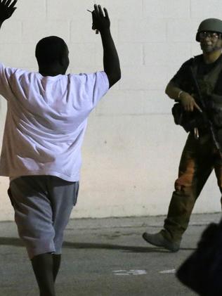 A man raises his hands as he walks near police after the shooting in Dallas. Picture: AP Photo/LM Otero.