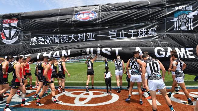 NOT THIS YEAR: Port Adelaide and St Kilda players run through the banner together to celebrate last year’s AFL match in China. This year’s repeat contest has been rescheduled to Melbourne due to the coronavirus. Picture: DAVID MARIUZ (AAP),