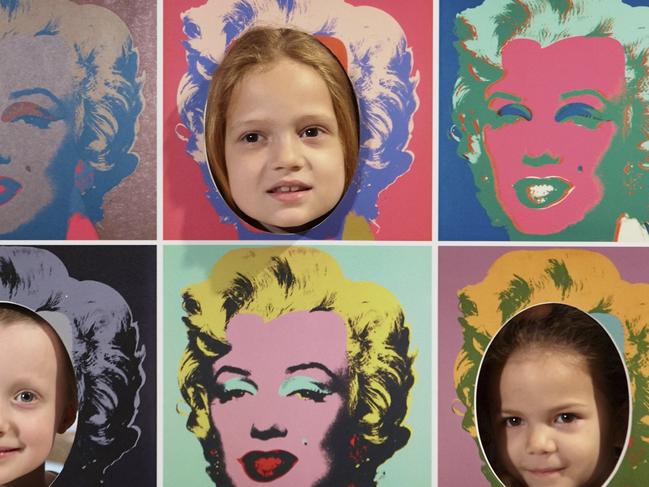 Children pose to have their photo taken with the Pop Faces featuring reproductions of Andy Warhol’s Marilyn Monroe, 1967, Frederick R Weisman Art Foundation, Los Angeles, in the POP PLAY area in the Pop to popism exhibition at the Art Gallery of New South Wales. Photo: AGNSW/Jenni Carter © The Andy Warhol Foundation for the Visual Arts