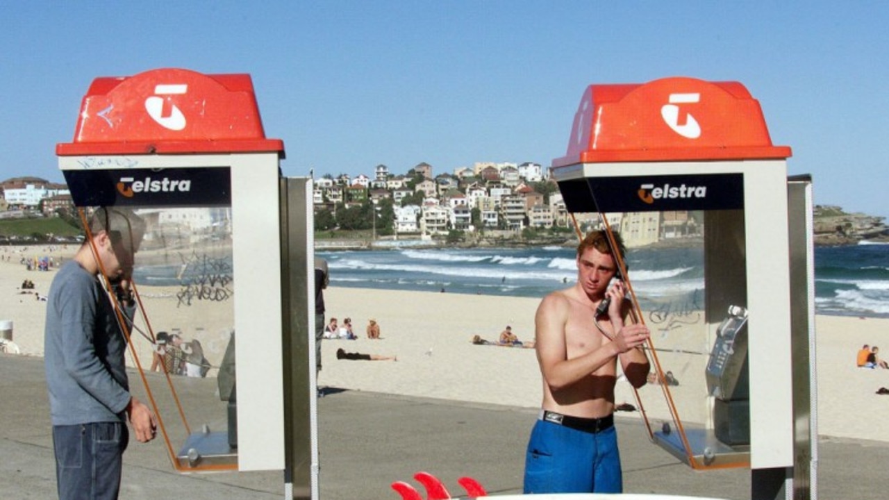 Beachgoers at Sydney's Bondi Beach make calls from Telstra phone boxes