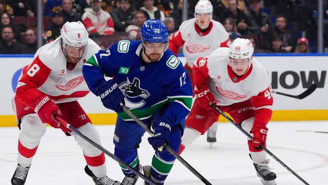 VANCOUVER, CANADA - FEBRUARY 2: Filip Chytil #72 of the Vancouver Canucks skates with the puck ahead of Ben Chiarot #8 and Jonatan Berggren #48 of the Detroit Red Wings during the third period of their NHL game at Rogers Arena on February 2, 2025 in Vancouver, British Columbia, Canada. (Photo by Derek Cain/Getty Images)