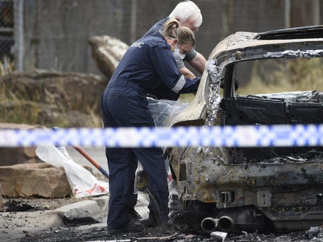 Forensics check out a burnt-out car believed to be linked to the shooting. Picture: Andrew Henshaw