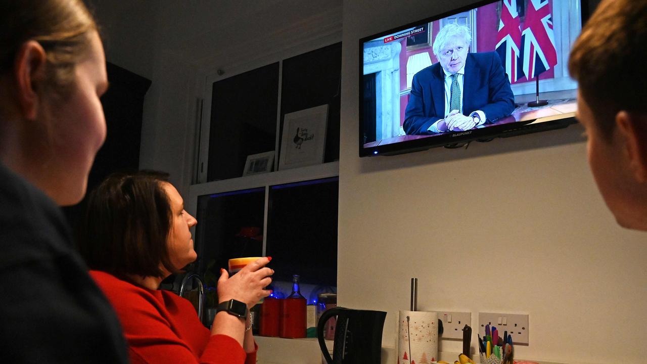 A family gather around the television in Liverpool to watch Boris Johnson give a televised message to the nation from 10 Downing Street in London. Picture: Paul Ellis/AFP