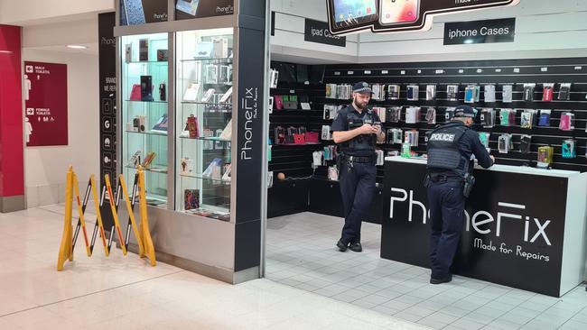 Police interview a shopkeeper in City Cross Arcade next to where a security guard was a stabbed