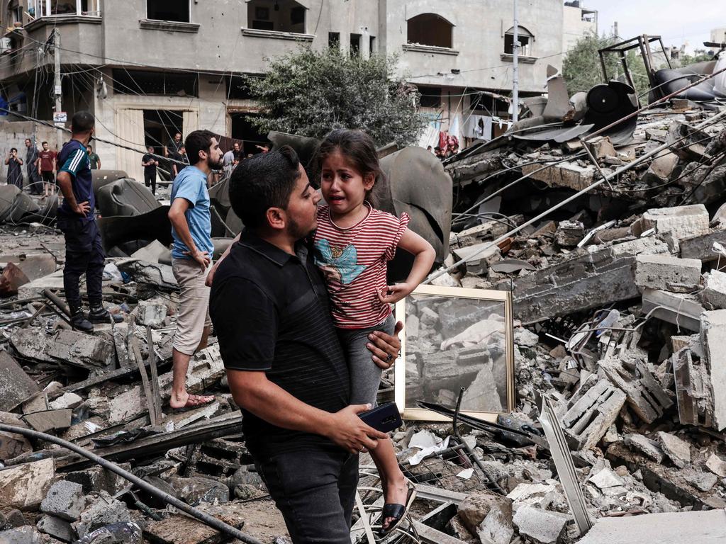 A man carries a crying child as he walks in front of a building destroyed in an Israeli air strike in Gaza City. Picture: AFP