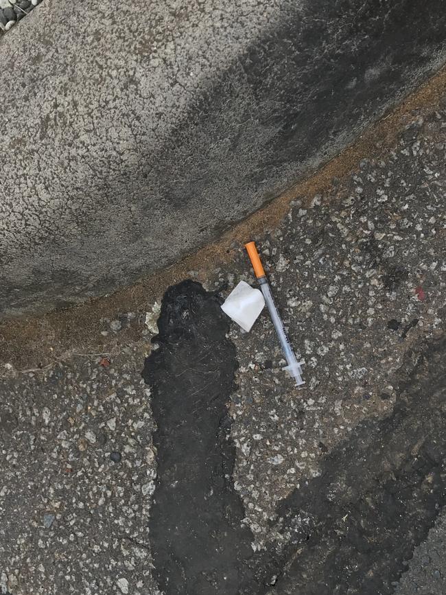 A syringe lies in the gutter.