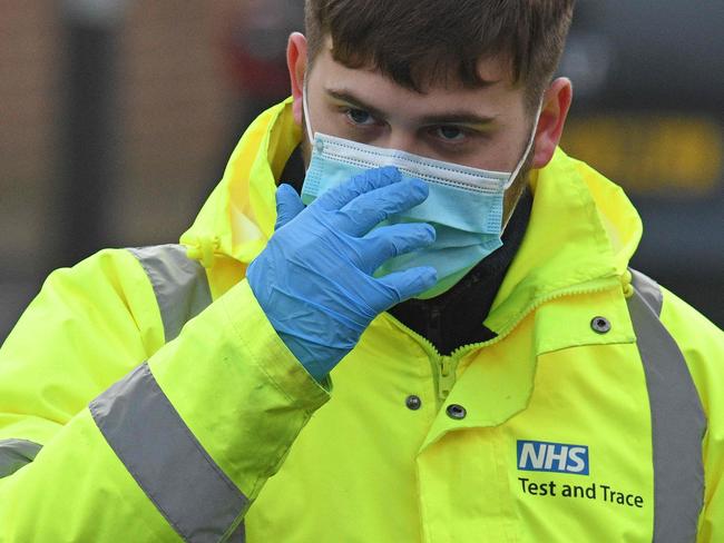 A worker wearing an NHS Test and Trace-branded jacket adjusts his mask as he works at a temporary COVID-19 testing facility, part of surge testing for the South African variant of Covid-19, at the Walsall Arena & Arts Centre in Walsall, central England on February 4, 2021. - The highly transmissible variant first identified in South Africa is spreading rapidly around the world, and was last week detected for the first time in the United States. (Photo by Oli SCARFF / AFP)