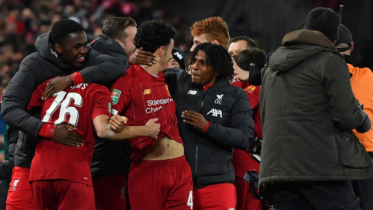 Curtis Jones is mobbed by teammates after scoring Liverpool’s winning penalty.