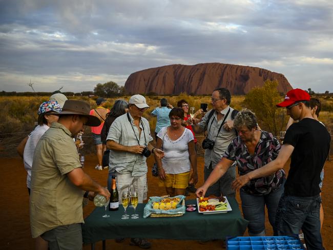 Wind gusts swept through as tourists take pictures of Uluru, also known as Ayers Rock from the dedicated sunset area near Uluru-Kata Tjuta National Park this week. Picture: AAP