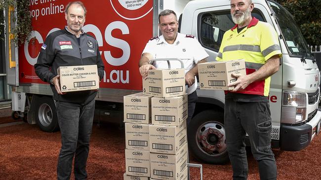 Collingwood Football Club operations director David Emerson (left), Salvation Army Project 614 director Maj Brendan Nottle and a Coles delivery driver.