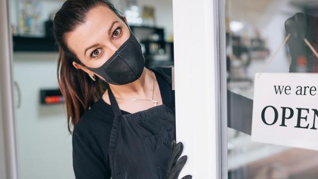 Happy business owner hanging an open sign during COVID-19, possibly because of the omnibus bill. Picture: iStock