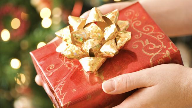 Hands holding Christmas gift with tree in background