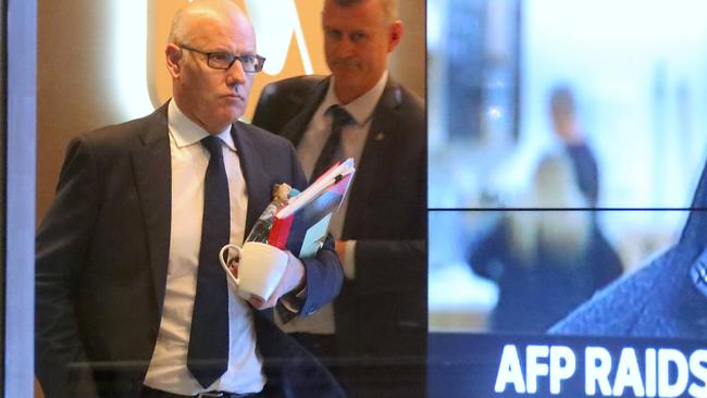 ABC executive editor John Lyons is followed by an AFP officer as they walk out of the main entrance to the broadcaster’s Sydney HQ. Picture: AAP