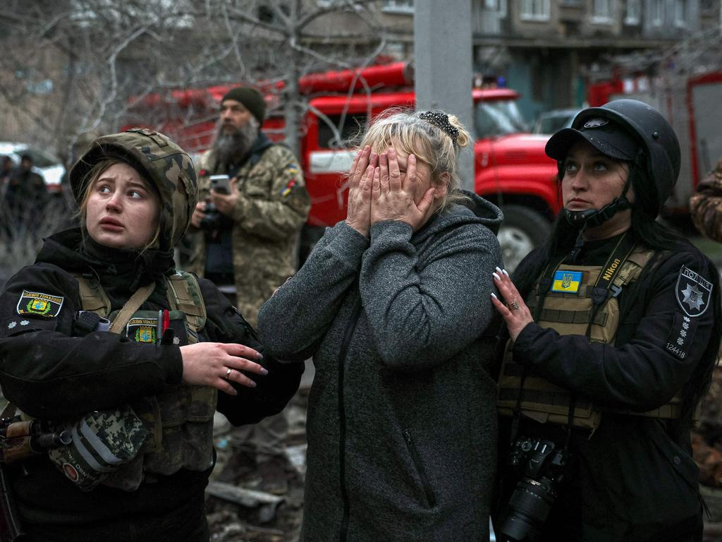 A distraught woman is comforted by rescuers in front of a partially destroyed residential building after a Russian strike in Sloviansk. Picture: AFP