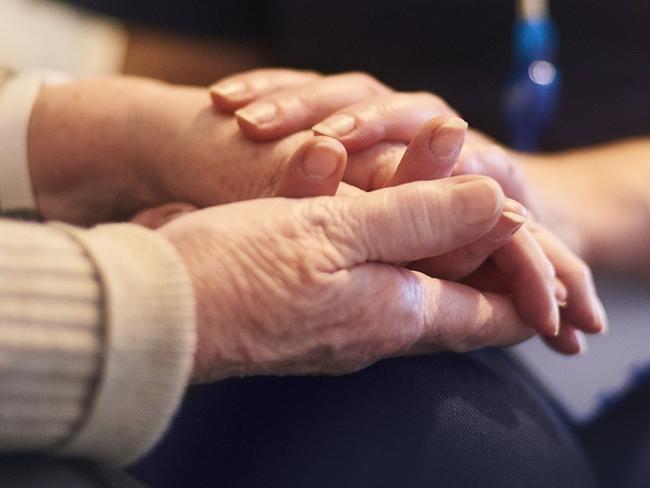 A female nurse consoles a senior patient at home, aged care generic