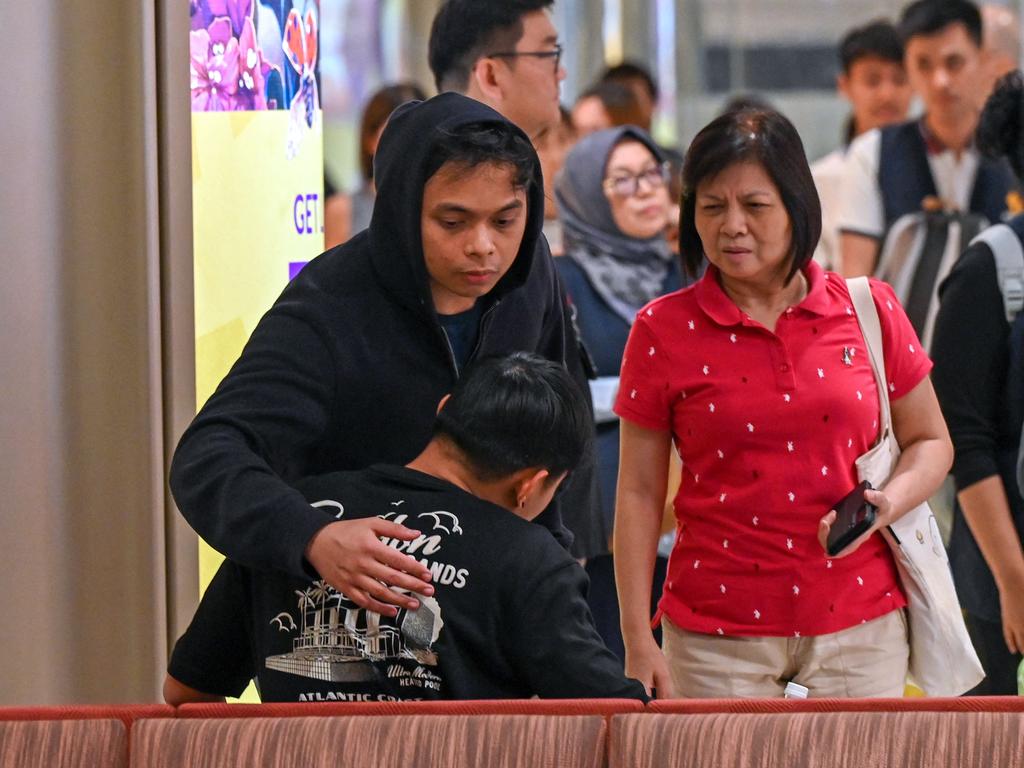 The passengers hug family members after flying from Bangkok to Singapore. Picture: AFP