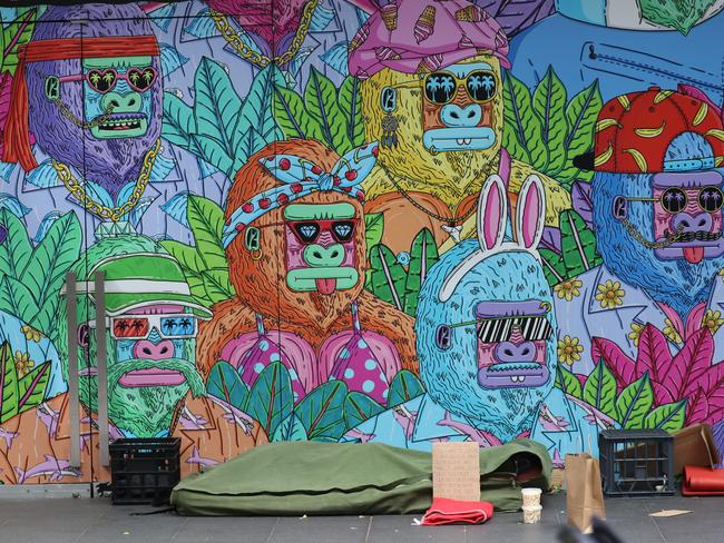 Someone sleeps below a mural in central Sydney. Picture: John Grainger