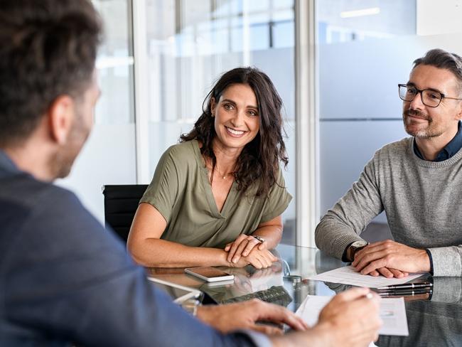 Smiling mature couple meeting with bank manager for investment. Beautiful mid adult woman with husband listening to businessman during meeting in conference room in modern office. Happy middle aged couple meeting loan advisor to buy a new home. Financial planning, advice generic