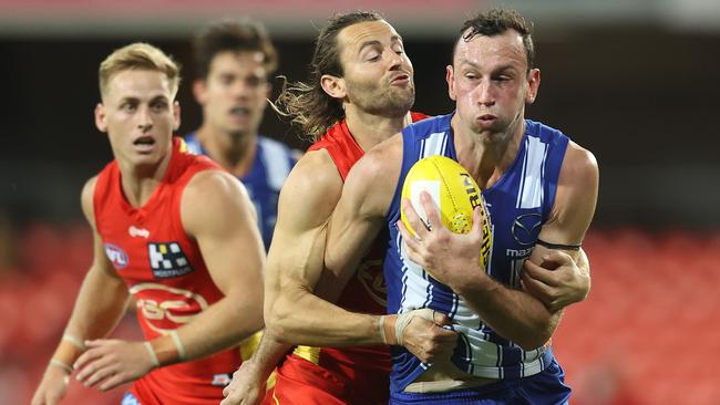 Gold Coast’s Lachie Weller wraps up North Melbourne’s Todd Goldstein in a strong tackle. Picture: Chris Hyde/Getty Images