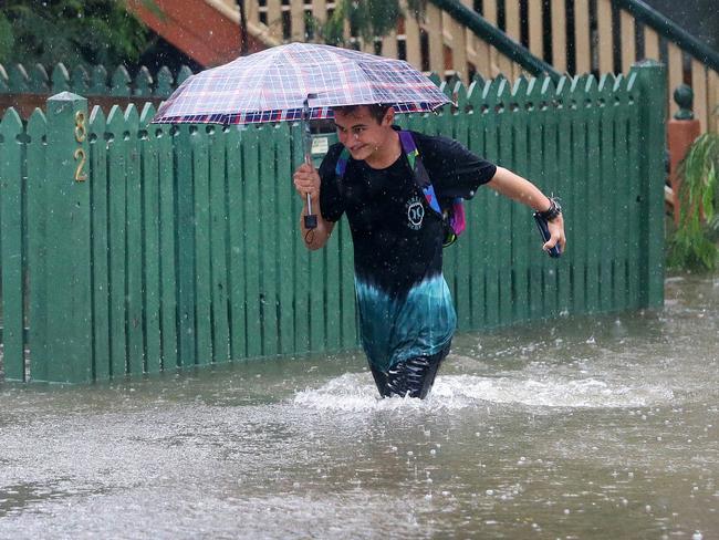 Rigby Wilshire wades through fllood waters to get to his home on Longlands st at East Brisbane. Rain from ex-cyclone Debbie causing flooding in Brisbane. Pic Darren England.