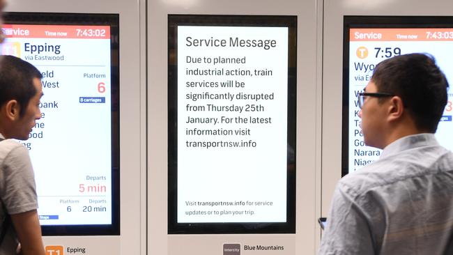 Commuters look at a timetable at Strathfield station. Picture: AAP