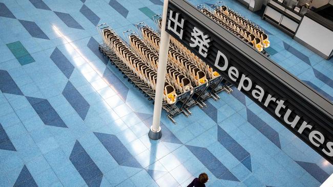 A person walks in an empty departures hall at Tokyo's Haneda international airport on January 25, 2022. - More than 370,000 people are left in limbo by Japan's coronavirus border rules, which bar almost all new arrivals and are the strictest in the G7. (Photo by Philip FONG / AFP) / TO GO WITH Health-virus-Japan-immigration-education,FOCUS by Etienne Balmer and Katie Forster