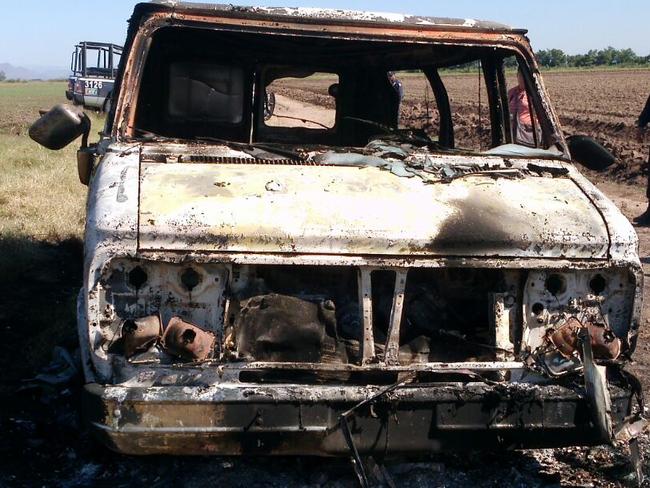 In this Nov. 21, 2015 photo, Mexican authorities inspect a burnt out van suspected to belong to a couple of Australian tourists missing for more than a week, in Sinaloa, Mexico. Two burned bodies where reportedly found inside the vehicle. The toursits, Dean Lucas and Adam Coleman were traveling from Edmonton, Canada and were scheduled to arrive on Nov. 21 in the city of Guadalajara but failed to appear. (AP Photo)