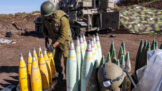 An Israeli army soldier adjusts the tip of a 155mm artillery shell near a self-propelled howitzer deployed at a position near the border with Lebanon. Picture: AFP.