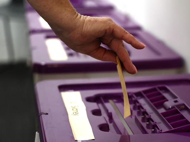 A voter places their vote into a polling box at a voting centre in central Sydney on October 3, 2023. Early voting opened on October 3 across a swathe of Australia on a reform that would recognise Indigenous people in the 1901 constitution for the first time. (Photo by DAVID GRAY / AFP)