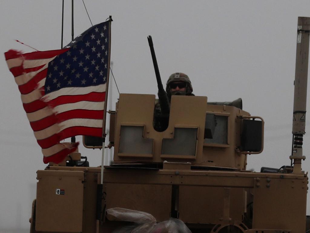 A US soldier riding an armoured personnel carrier as a line of US military vehicles patrol Syria's northern city of Manbij.