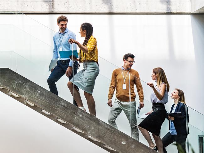 A rear view of group of young businesspeople walking up the stairs.