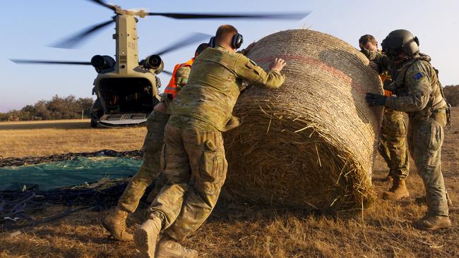 Soldiers and pilots unload hay bales from Chinook helicopters. Picture: ADF